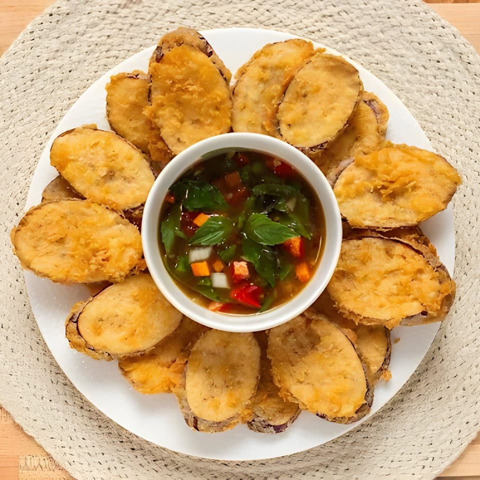Crispy fried eggplant slices arranged around a bowl of sweet chili dipping sauce with herbs.