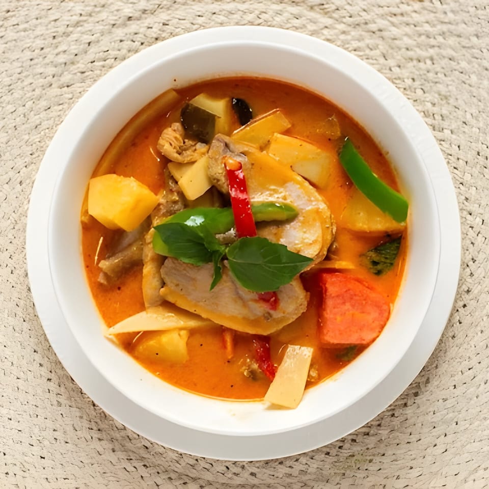 A bowl of M Thai Kitchen's red curry with chicken, bamboo shoots, and basil.